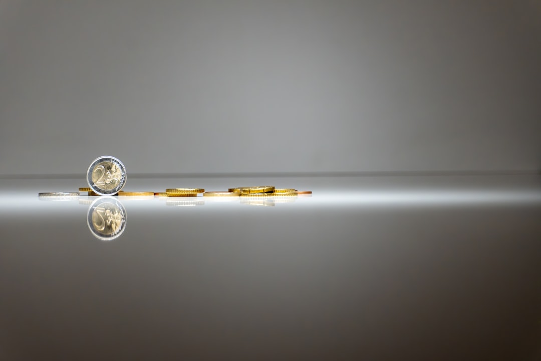 a-pair-of-gold-coins-sitting-on-top-of-a-reflective-surface-5ovkuhlw63u